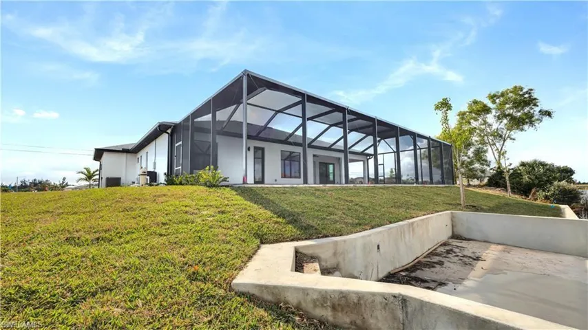 Back of property featuring a lawn, glass enclosure, and central AC unit