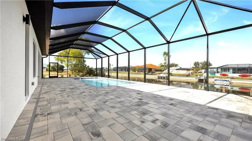 View of pool featuring glass enclosure, a water view, and a patio