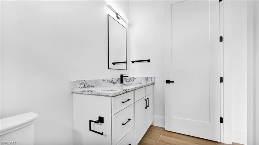 Bathroom featuring vanity, hardwood / wood-style flooring, and toilet