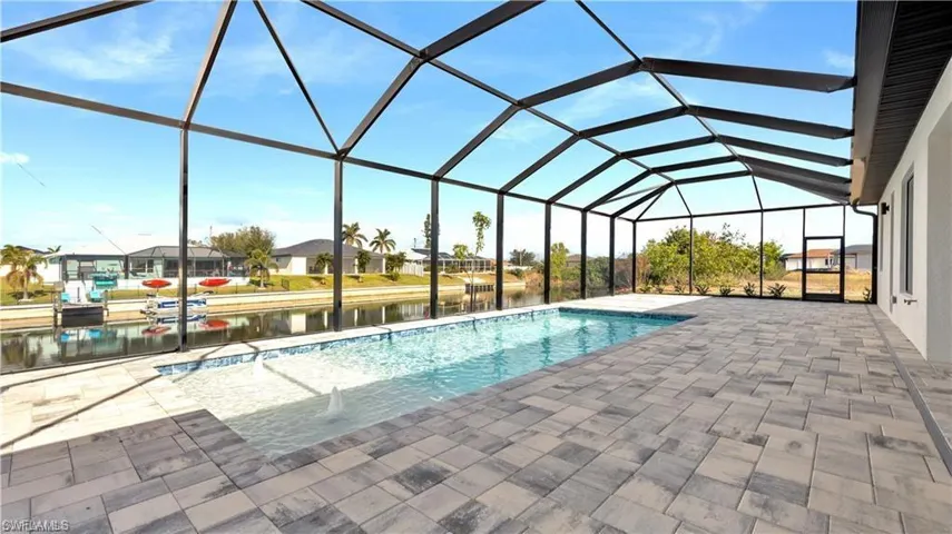 View of swimming pool with glass enclosure, a water view, and a patio