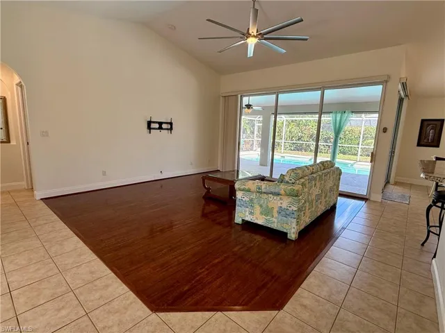 Living area with light tile patterned floors, arched walkways, a ceiling fan, and high vaulted ceiling