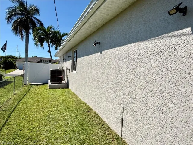 View of side of property featuring stucco siding and a gate