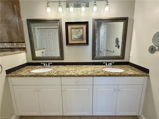 Full bath featuring double vanity and light tile patterned floors