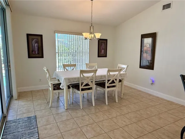 Dining space with light tile patterned floors, a chandelier, and vaulted ceiling