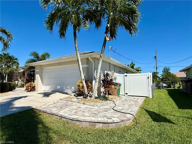 View of side of property with stucco siding, a gate, driveway, and a garage