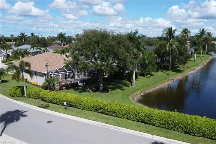 Drone / aerial view, notice tree filled landscape along with high hedge for privacy along the side road.