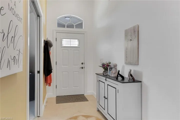 Foyer entrance with light tile patterned floors and baseboards, transom window above new front door