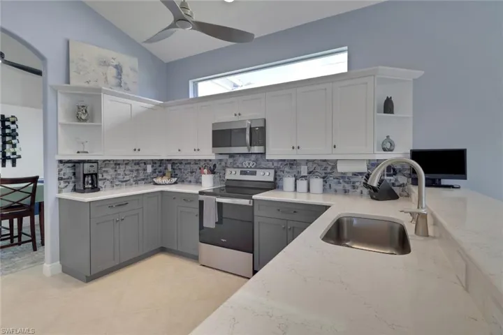 Kitchen well lit featuring transom above cabinets with plenty of room to decorate as you wish and light stone countertops, and new cabinet fronts.