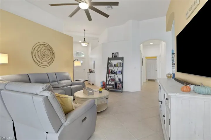 Living room facing toward the laundry and garage hallway featuring arched walkways