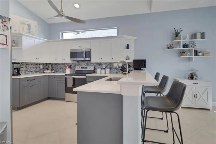 Kitchen with high ceilings showcasing the breakfast bar, dining to the right still has plenty of room with shelves and stand-free cabinet.