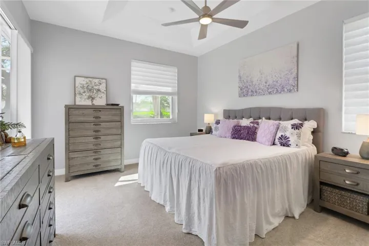 Bedroom featuring new light colored carpet, a tray ceiling, and a ceiling fan, night stand window shade opens from the top (for privacy) and the bottom.  Notice slide glass door private entrance to the lanai.