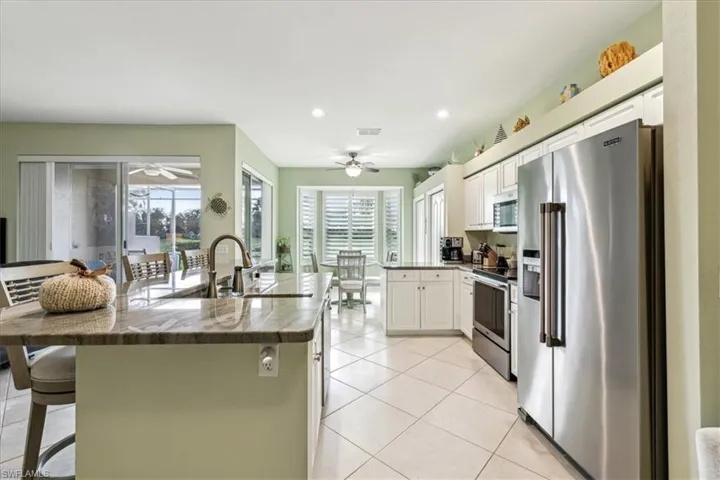 Kitchen featuring appliances with stainless steel finishes, a breakfast bar, white cabinetry, and sink