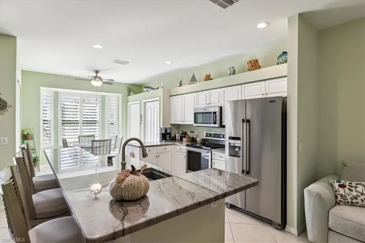 Kitchen with white cabinets, a breakfast bar, light tile patterned flooring, sink, and stainless steel appliances