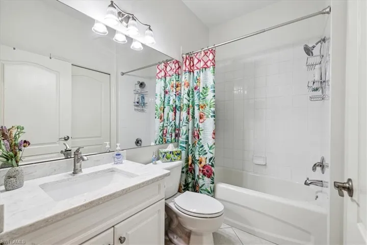 Full bathroom with toilet, shower / bath combo with shower curtain, vanity, and tile patterned flooring