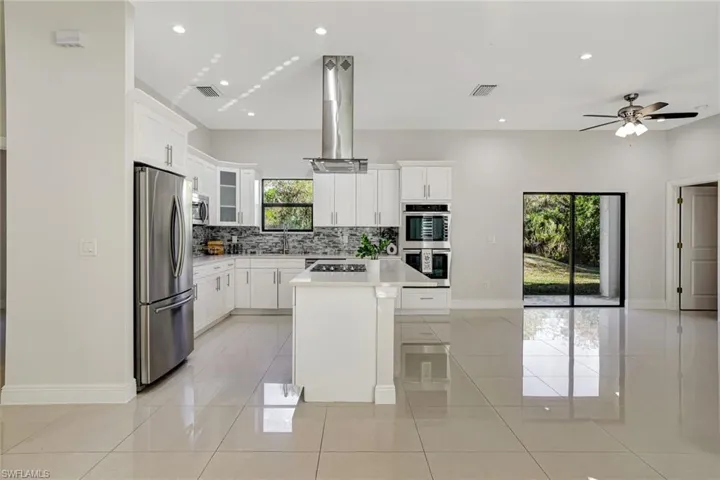 Kitchen with white cabinets, recessed lighting, appliances with stainless steel finishes, a kitchen island, and light tile patterned flooring