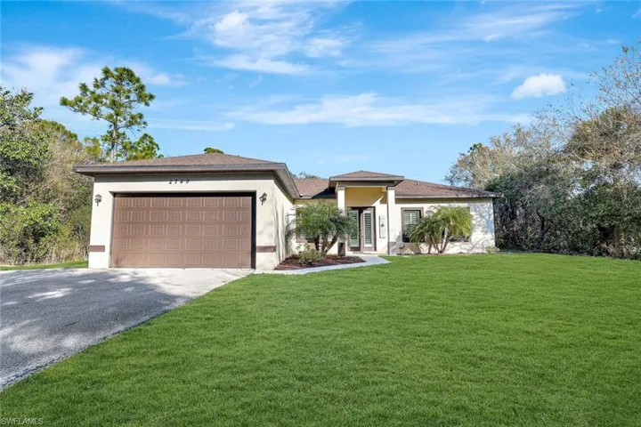 Prairie-style home with stucco siding, driveway, a front yard, and a garage