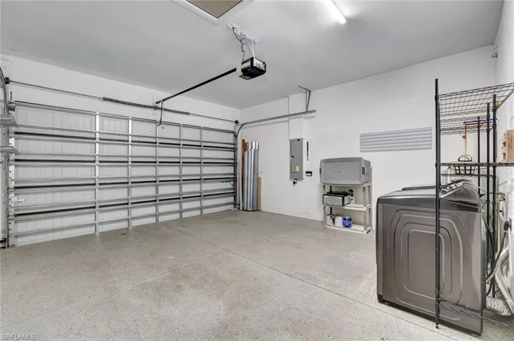 Garage featuring washer / dryer, electric panel, and a garage door opener
