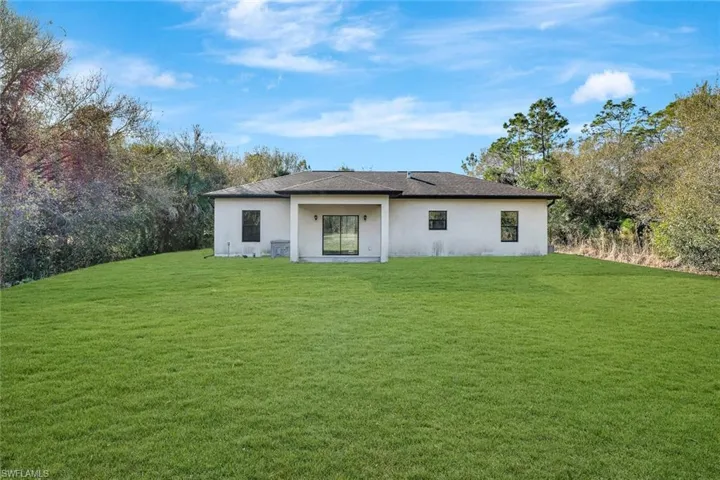 Back of house with a yard and stucco siding