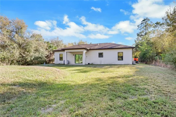 Back of property with a lawn, stucco siding, and a patio area