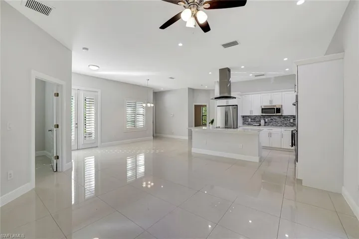 Unfurnished living room featuring a ceiling fan, light tile patterned flooring, a chandelier, and recessed lighting