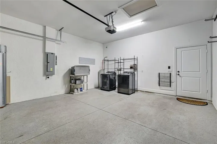 Garage featuring washer and dryer, electric panel, and a garage door opener