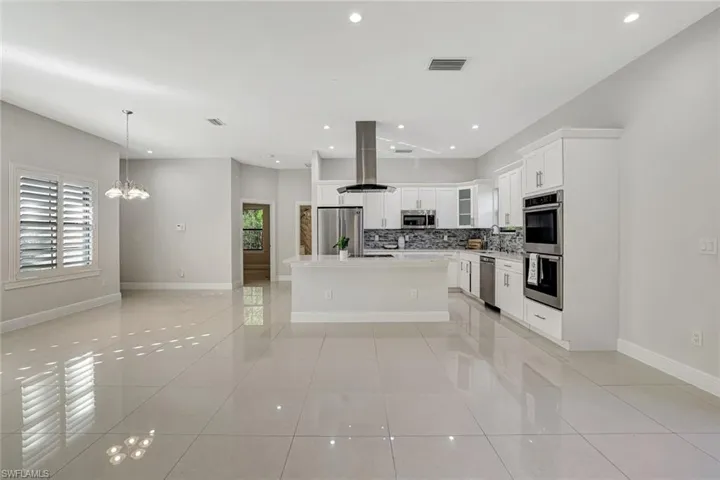 Kitchen featuring open floor plan, white cabinetry, recessed lighting, a kitchen island, and pendant lighting
