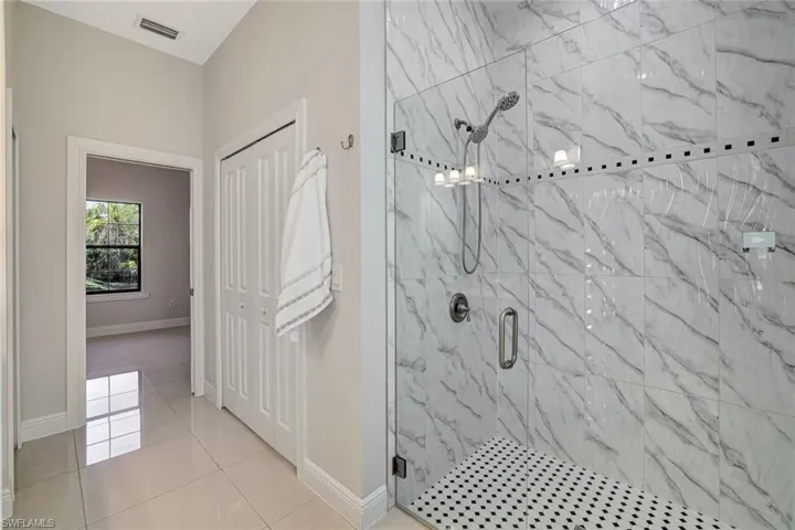 Bathroom with a marble finish shower and light tile patterned floors