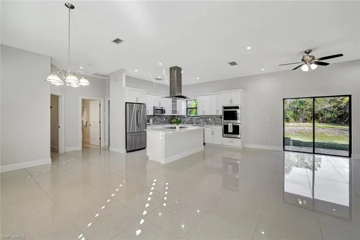 Kitchen with open floor plan, white cabinetry, appliances with stainless steel finishes, a kitchen island, and recessed lighting