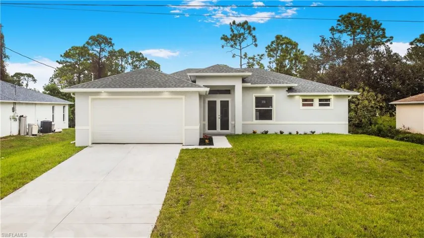 View of front of home with a garage, a front yard, central AC unit, and french doors