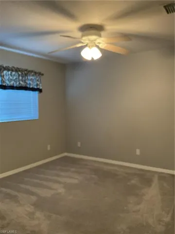 Carpeted spare room featuring ceiling fan