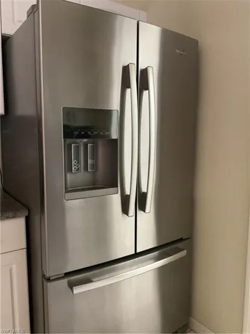 Details featuring white cabinets and stainless steel fridge