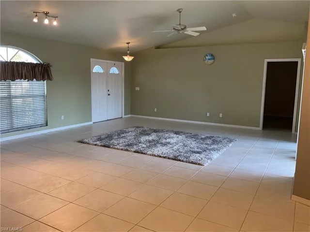 Tiled foyer entrance with vaulted ceiling and ceiling fan