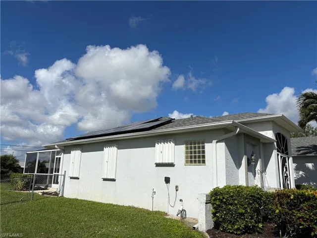 View of property exterior with solar panels and accordian hurricane shutters
