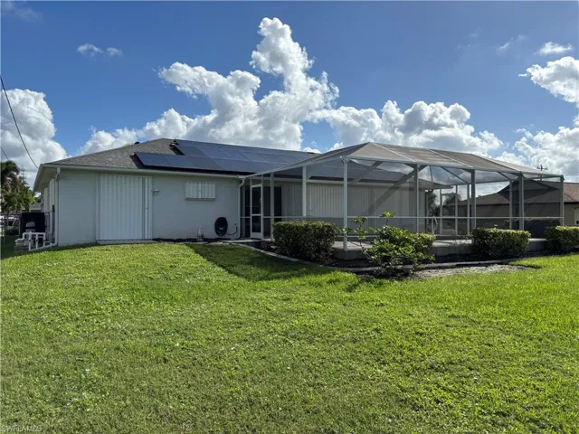 Back of house featuring solar panels, hurricane shutters that enclose lanai