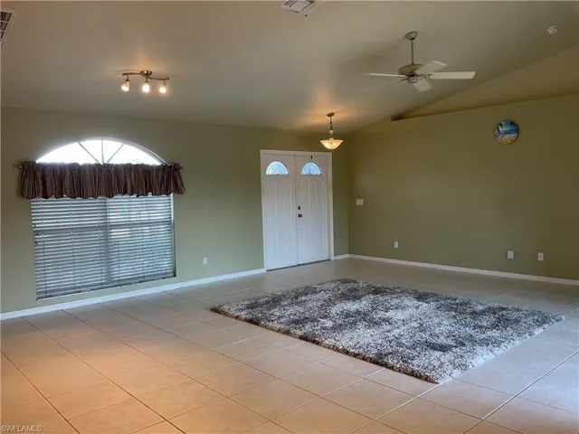 Entryway with ceiling fan, lofted ceiling, and light tile patterned floors