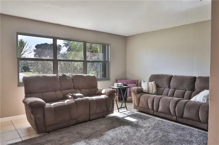 Living area featuring large windows, light-toned walls, and tile flooring