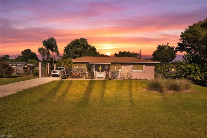 Single-story residence featuring a concrete driveway, mature landscaping, and an enclosed front entry