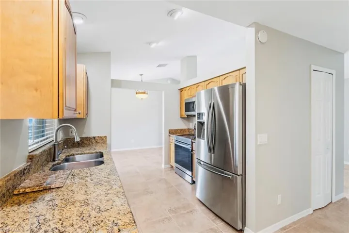 Kitchen featuring granite countertops, stainless steel appliances, recessed lighting, oak cabinetry, and neutral tile patterned flooring