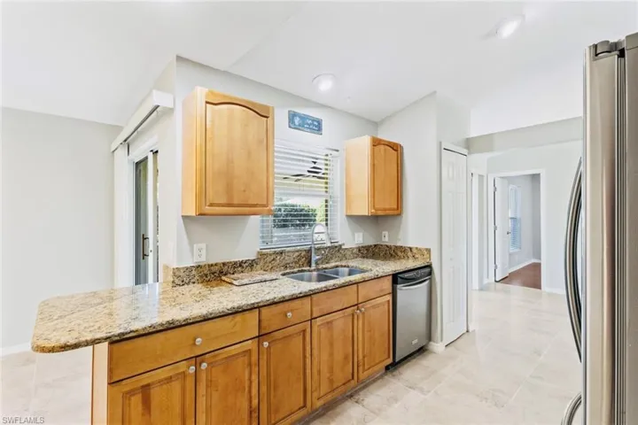 Kitchen featuring granite countertops, stainless steel appliances, recessed lighting, oak cabinetry, and neutral tile patterned flooring