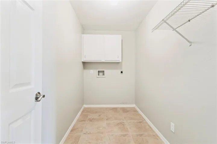 Large Laundry room with washer hookup, electric dryer hookup, cabinet space, and neutral tile patterned floors