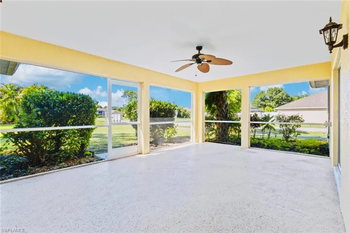 Large screened in Lanai featuring speckled flooring, ceiling fan, and outside lighting