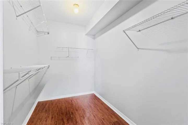 Spacious primary closet featuring  wood floors