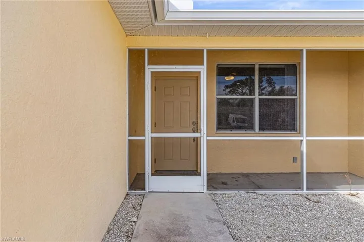 Property entrance featuring stucco siding and a screened lanai