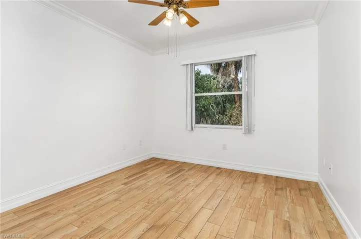 Unfurnished bedroom with light wood-style tile flooring, crown molding, and ceiling fan