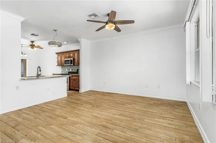 Unfurnished living room featuring ceiling fan, wood-style tiled floors