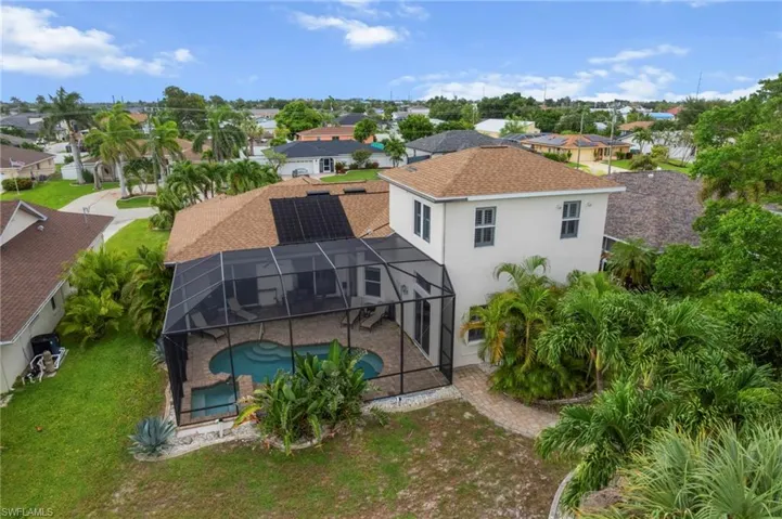 Rear view of property featuring an outdoor pool, a lanai, stucco siding, a sunroom, and a residential view