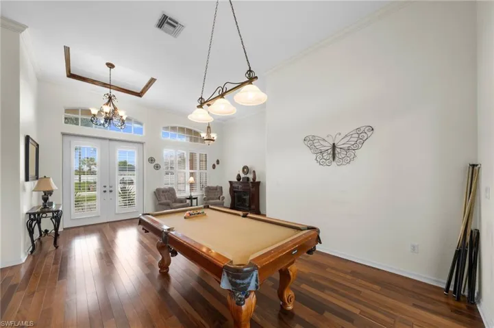 Playroom with french doors, dark wood-style floors, crown molding, billiards table, and hanging lights