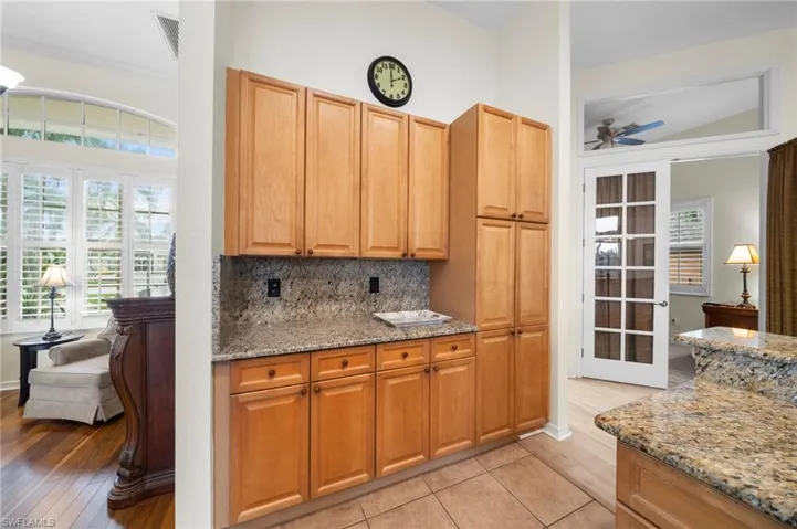 Kitchen featuring light stone counters, backsplash, a ceiling fan, and french doors