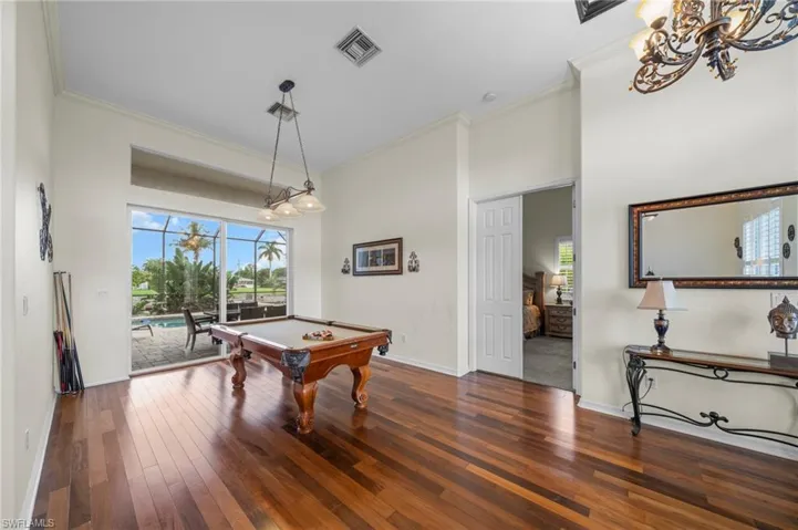 Rec room featuring ornamental molding, dark wood-style floors, pool table, and a chandelier