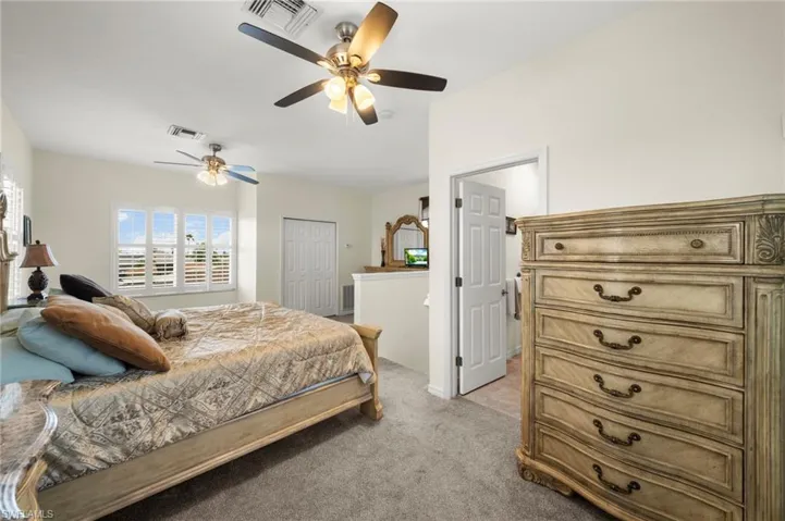 Bedroom featuring a closet, light colored carpet, and ceiling fan